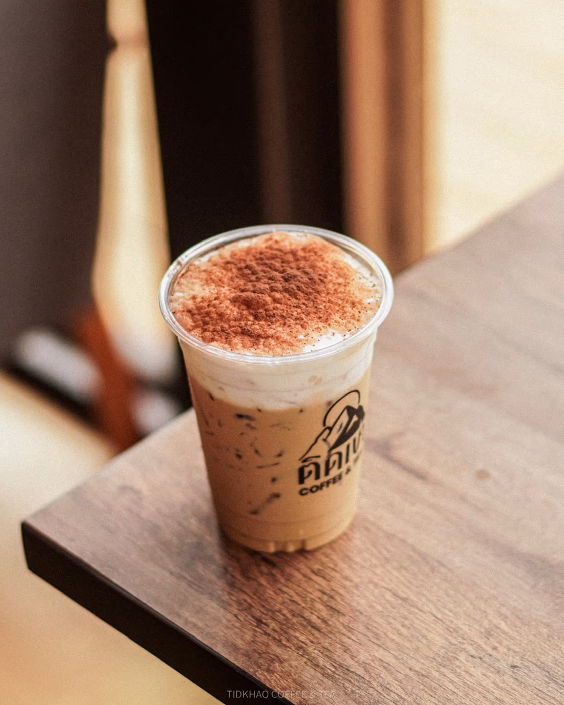 กาแฟเย็นโรยผงโกโก้บนโต๊ะไม้